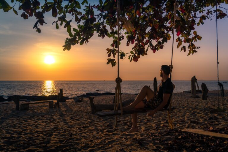 Man,Enjoying,The,Sunset,On,The,Beach,On,A,Swing
